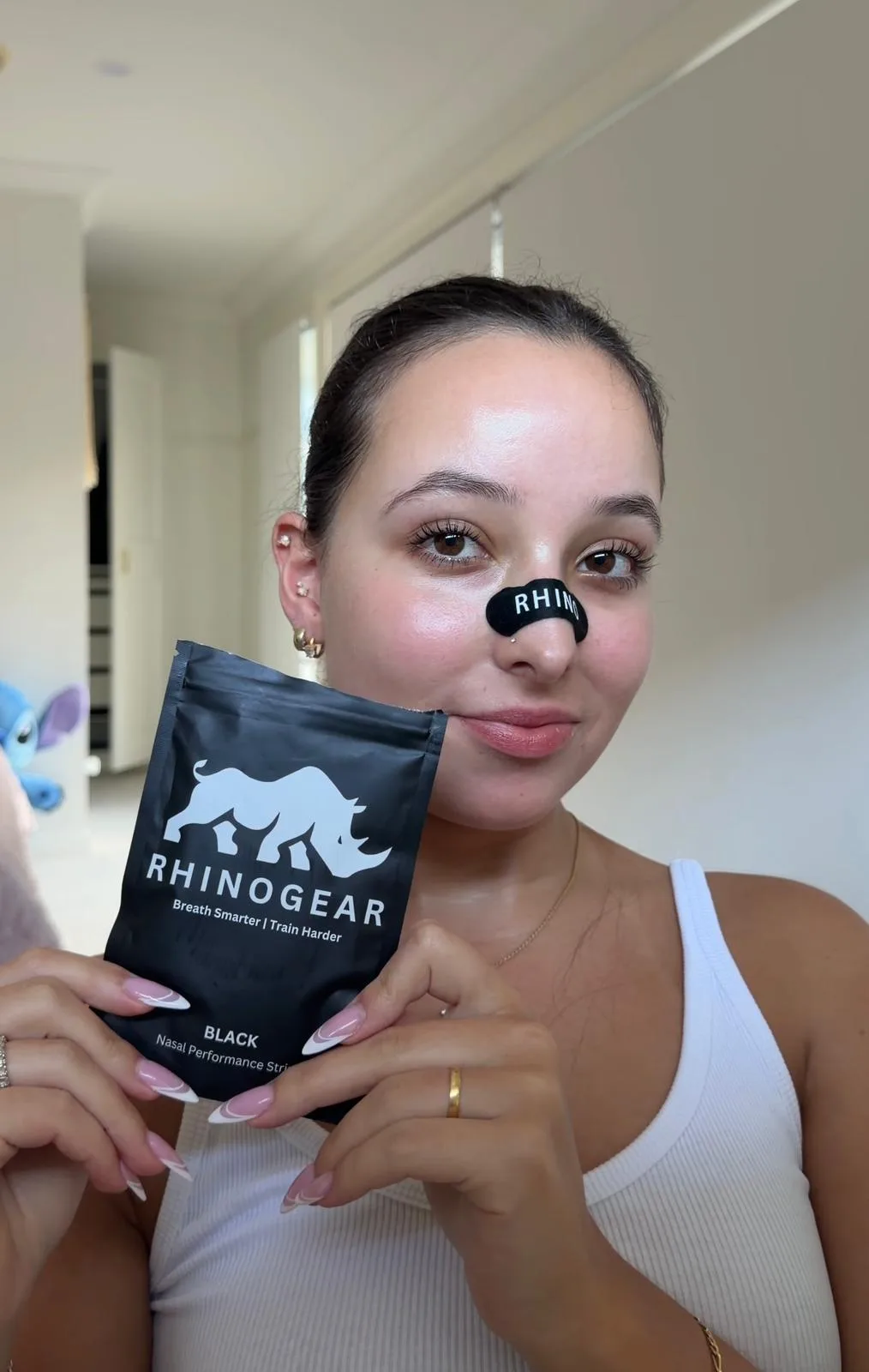 Australian customer wearing a black RhinoGear nasal strip while holding the 30-pack pouch